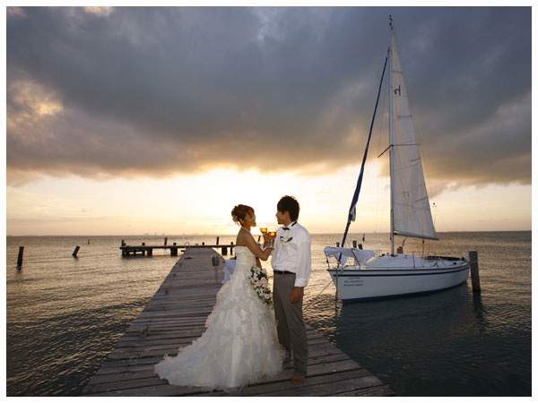 Pareja de novios brindando en el muelle junto a velero durante 