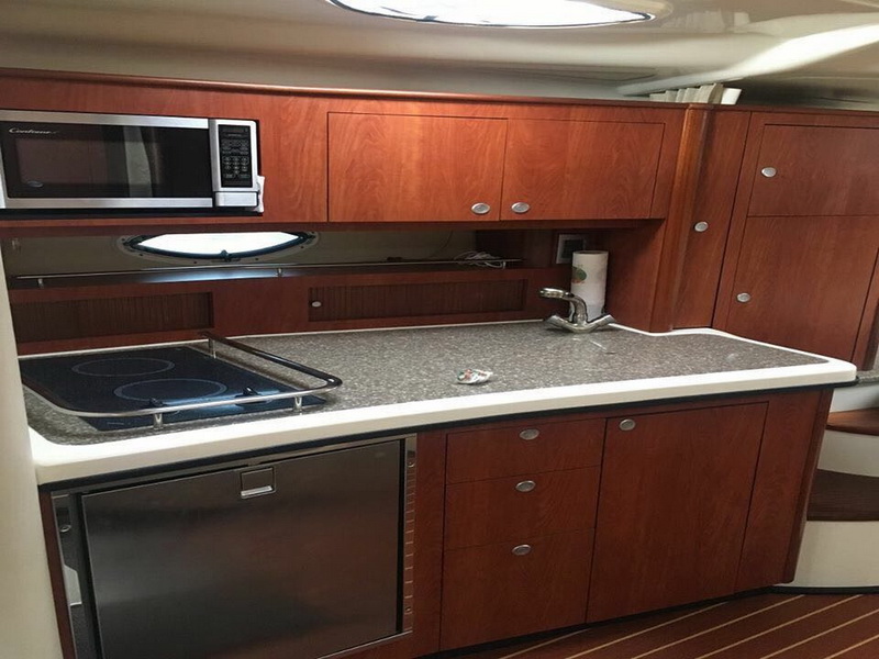 Cocina completa del yate deportivo Monterrey con placa de inducción, microondas y cabinetería de teca en Cancún