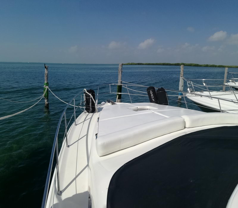 Bow sun pads of 41 ft Sea Ray flybridge yacht anchored near mangroves in the turquoise Cancun lagoon, private boat rental
