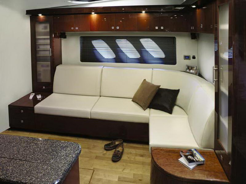 Luxury salon lounge aboard Sea Ray 55 ft yacht charter with white leather L-shaped sofa and dark wood panel accents