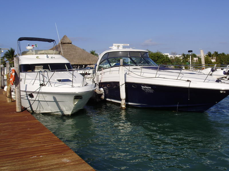 Two luxury charter yachts including Sea Horse 56 ft moored at tropical Cancún marina with thatched palapa in background