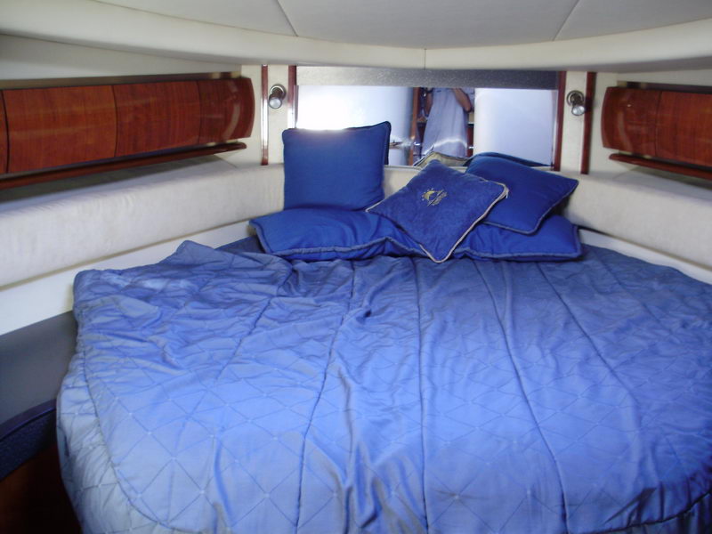 yacht rental with blue quilted bedding and mahogany cabin trim Cancún