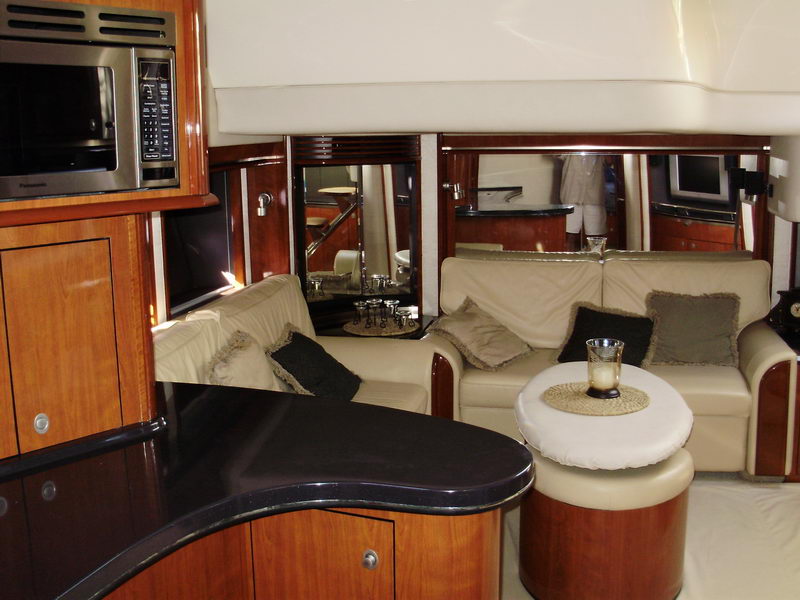 Main salon of Sea Horse 56 ft luxury yacht with lounge sofas, galley microwave bar and mahogany entertainment cabinet
