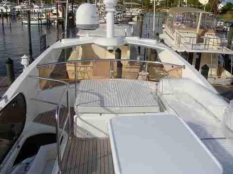 Foredeck of Sunseeker 56 ft charter yacht at marina showing teak deck, sun pad and navigation equipment from stern