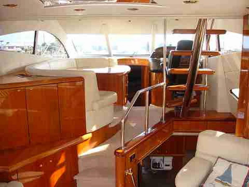 Interior salon of Sunseeker 56 ft yacht showing warm mahogany accents, cream upholstery, staircase and helm area