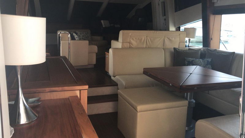 Interior salon of Sunseeker 64 ft luxury yacht with tan leather armchairs, folding tables, wood accents and silver floor lamps