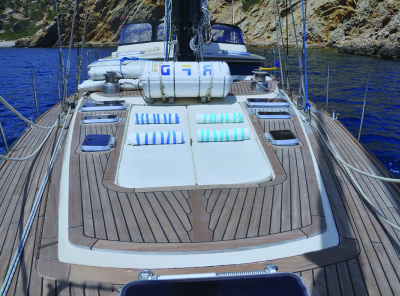 Proa de teca con tumbona acolchada y toallas a rayas en el yate velero Zulu de 66 pies, charter privado Caribe Cancún