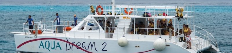 Catamarán Aqua Dream 2 lleno de buceadores con chalecos salvavidas sobre las aguas turquesa del arrecife de Cozumel