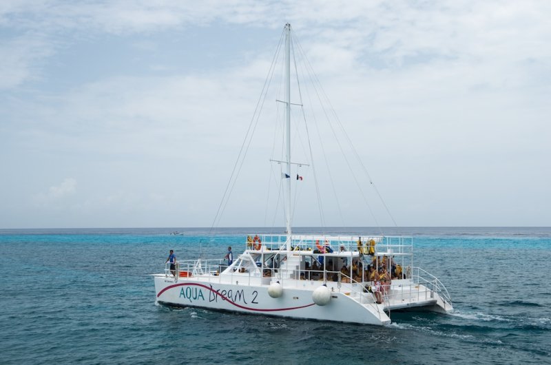 Catamarán Aqua Dream 2 navegando sobre el agua turquesa del Caribe cerca de la línea del arrecife de Cozumel
