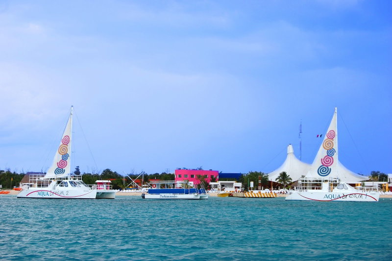 Dos catamaranes Aqua Dream amarrados en el colorido club de playa Playa Mia con carpas blancas en Cozumel