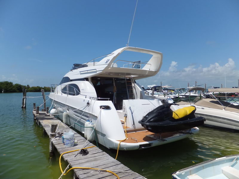 Stern of Azimut 60 ft yacht at Cancún marina with flybridge, boarding staircase and jet ski on teak swim platform