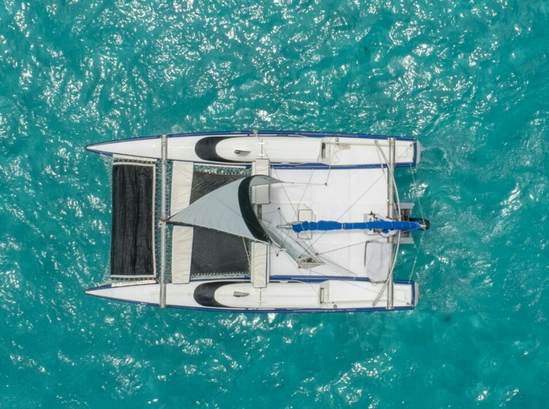 Aerial overhead view of Catamaran Eagle Jazz trimaran moored on turquoise Caribbean water, private sailing charter Cancun intimate groups