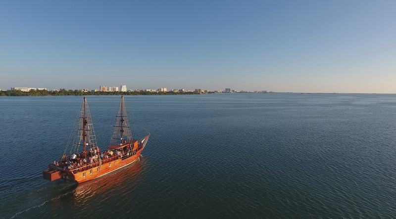 The Columbus Spanish galleon cruising the wide blue Nichupte Lagoon with the Cancun hotel zone skyline on the horizon