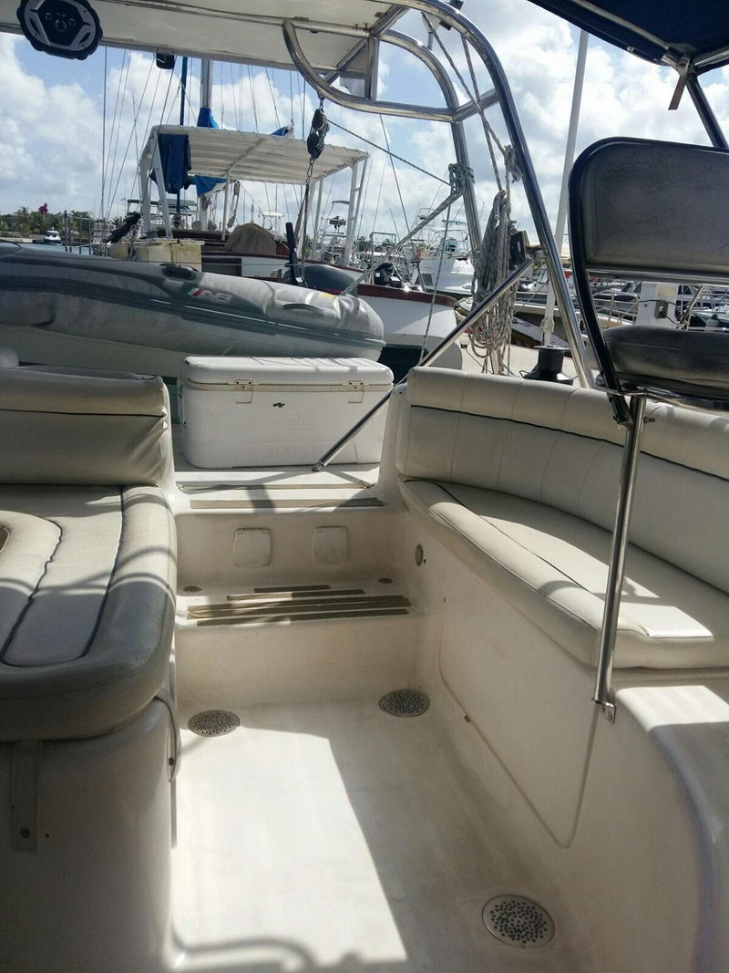 Amplia cabina del catamarán de Cozumel con asientos acolchados, hielera y dinghy en la marina