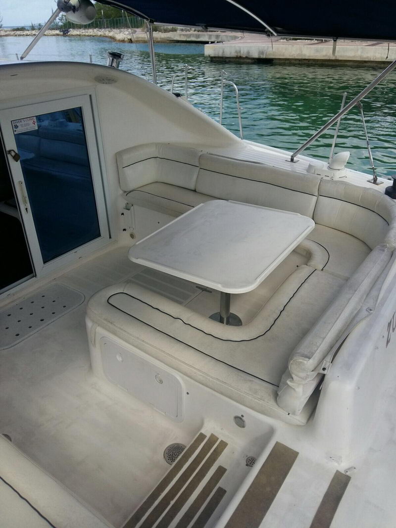 Mesa de comedor y asientos envolventes en la cabina del catamarán Lavezzi 42 junto a las aguas turquesa de Cozumel