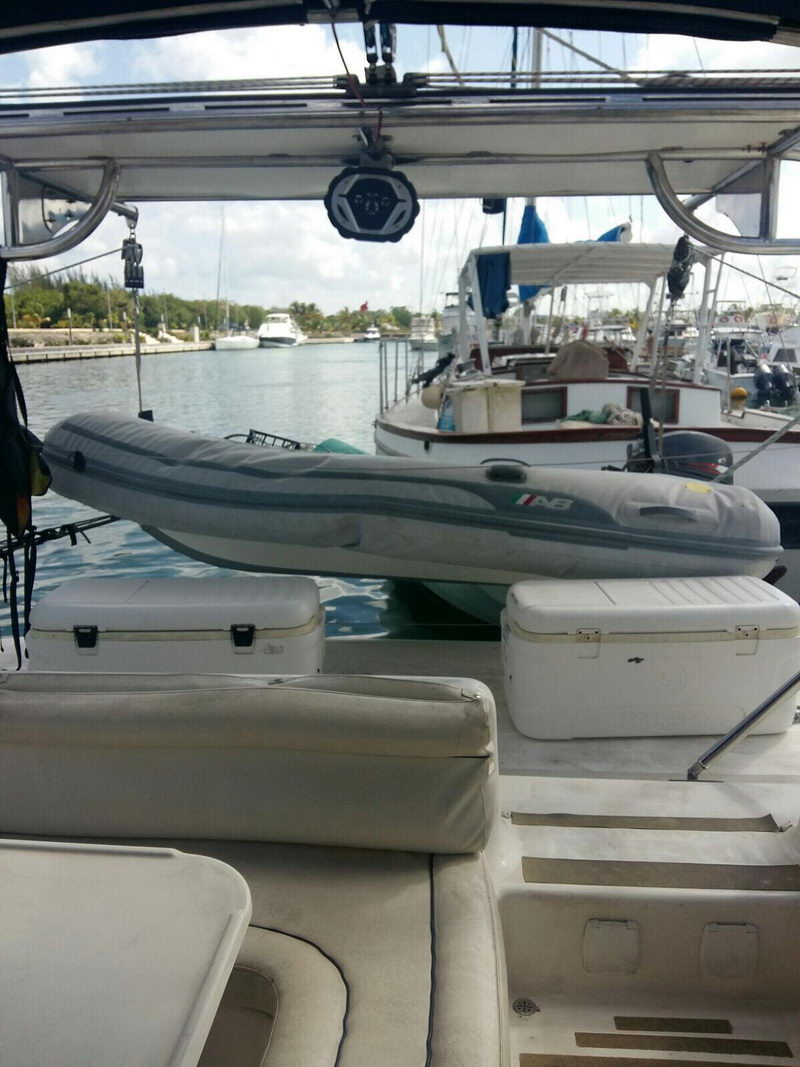 Cubierta de popa del catamarán de vela de Cozumel con dinghy en pescantes, hieleras y asientos de sol frente a la marina