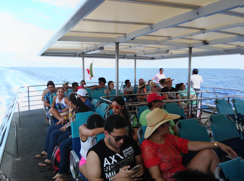 Pasajeros disfrutando la brisa marina y las vistas del Caribe desde la cubierta superior al aire libre del ferry a Cozumel