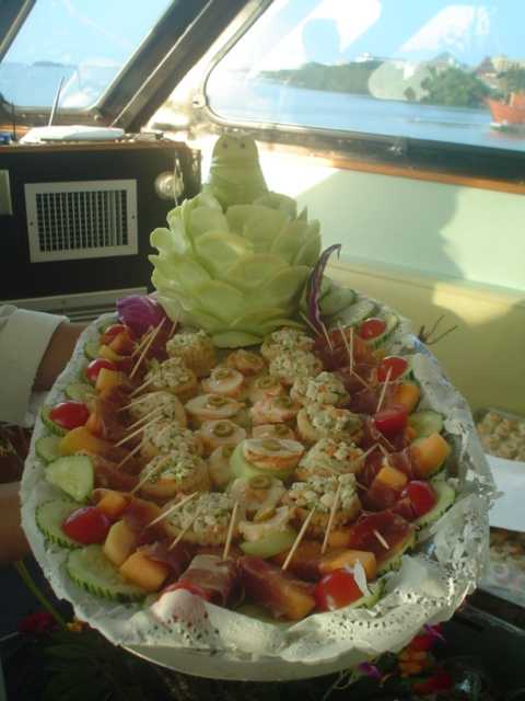 Elaborada charola de canapés de camarón y bocadillos con un centro de pepino tallado servida a bordo del Discovery
