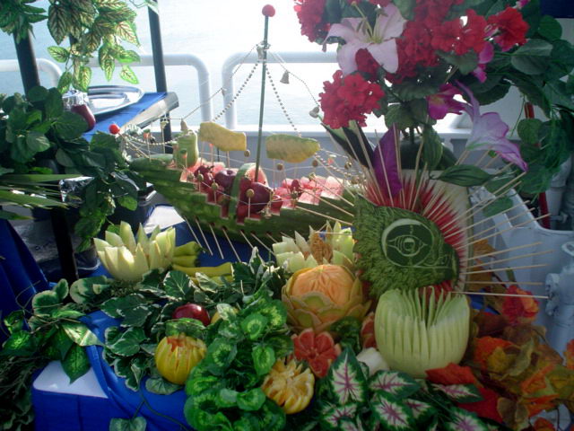 Generoso bufé de fruta tallada y flores montado en la cubierta del barco Discovery con vista al mar