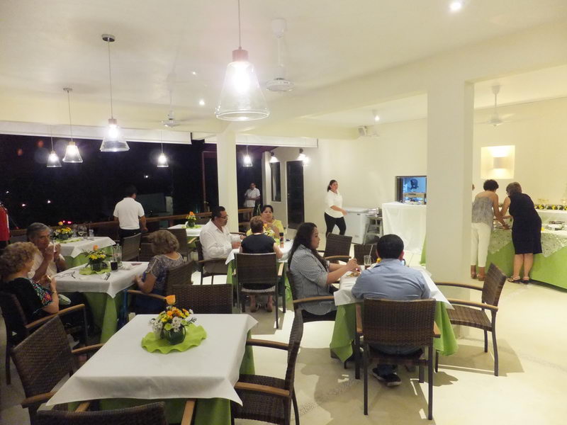Indoor dining room at Sunset Grill Isla Mujeres with white-clothed tables, hanging lights and a buffet set up for a private group event