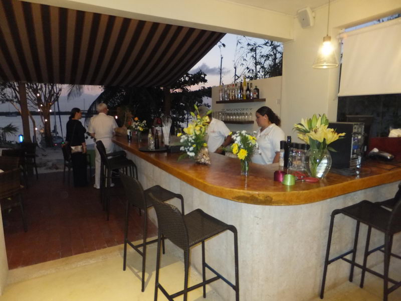 Beachfront bar at Sunset Grill Isla Mujeres with fresh flowers and bartenders, overlooking the lagoon at sunset for private celebrations
