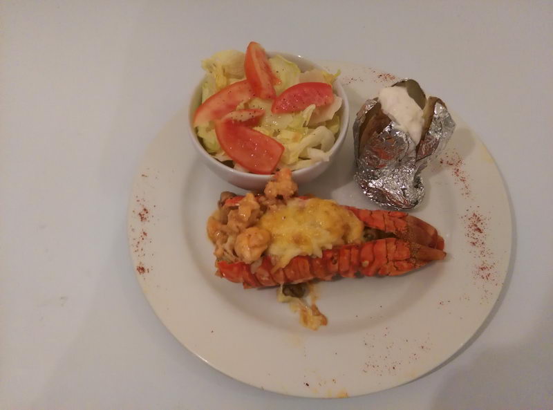 Gourmet grilled lobster tail dinner with baked potato and fresh salad served at Sunset Grill restaurant on Isla Mujeres