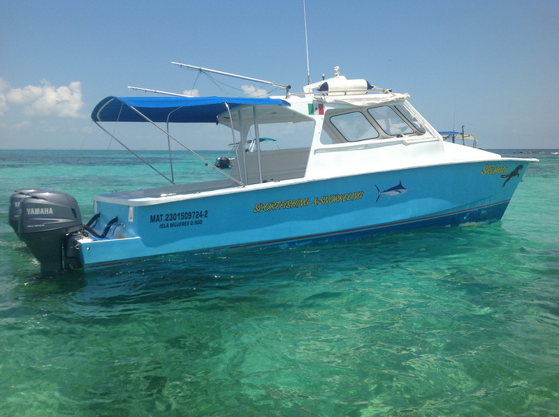 Barco privado amarrado en el muelle del centro de Isla Mujeres junto a los restaurantes frente al mar