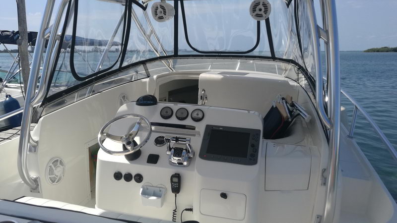 Puesto de mando del Intrepid 32 con volante, sonda, radio y manómetros bajo el hardtop sombreado, barco de pesca en Cancún