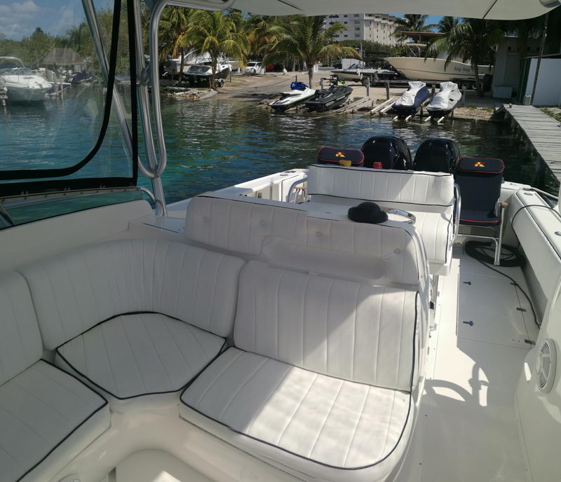 Amplia cabina con asientos acolchados blancos del bote deportivo Intrepid 32 en un muelle de canal en Cancún rodeado de palmeras