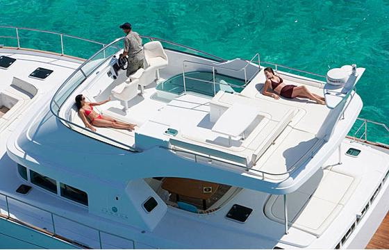 Guests sunbathing on the spacious flybridge of the Power Lagoon 46 catamaran over turquoise Caribbean water near Cancun and Isla Mujeres