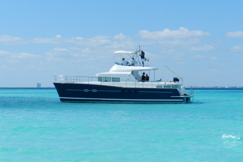 Navy-hulled Power Lagoon 46 catamaran anchored in brilliant turquoise water off Isla Mujeres near Cancun under a clear blue sky