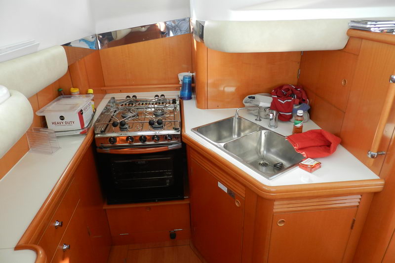 Full galley of the Power Lagoon 46 catamaran with gas stove, oven and double sink in warm wood cabinetry for onboard meals during Cancun charters