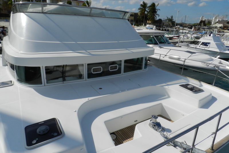 Wide foredeck and pilothouse windows of the Power Lagoon 46 catamaran docked among boats at the Cancun marina under a sunny sky