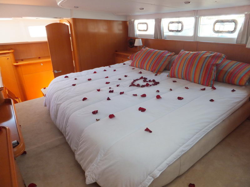Master cabin of the Power Lagoon 46 catamaran dressed with white linens and red rose petals in a heart for a romantic Cancun overnight charter