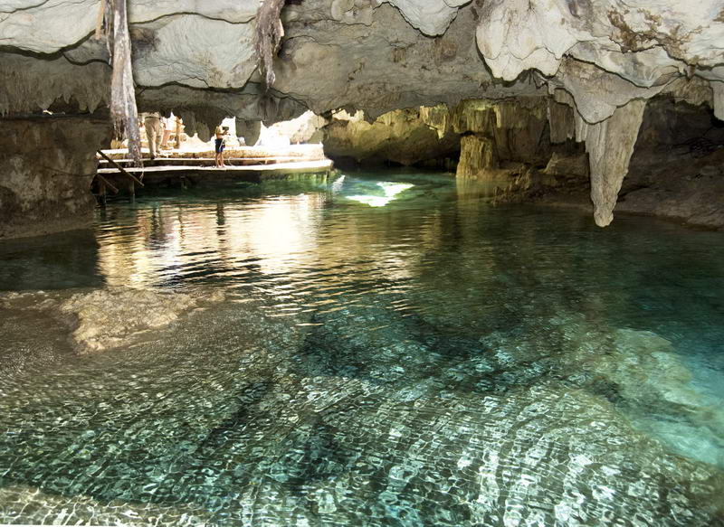 Crystalline cenote pool framed by ancient cave columns at Aktun Chen natural park between Akumal and Xel-Ha