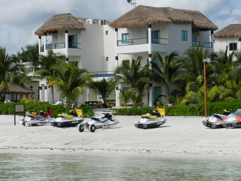 Wave runners lined up on the white sand in front of palapa-roofed beachfront villas at Maroma, Riviera Maya