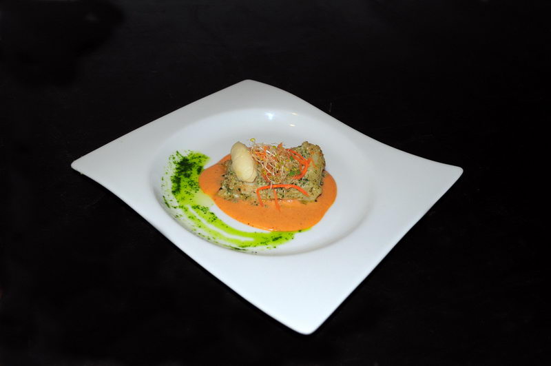 Gourmet herb-crusted fish on creamy red coral sauce with microgreens, plated on a white square dish by the 
