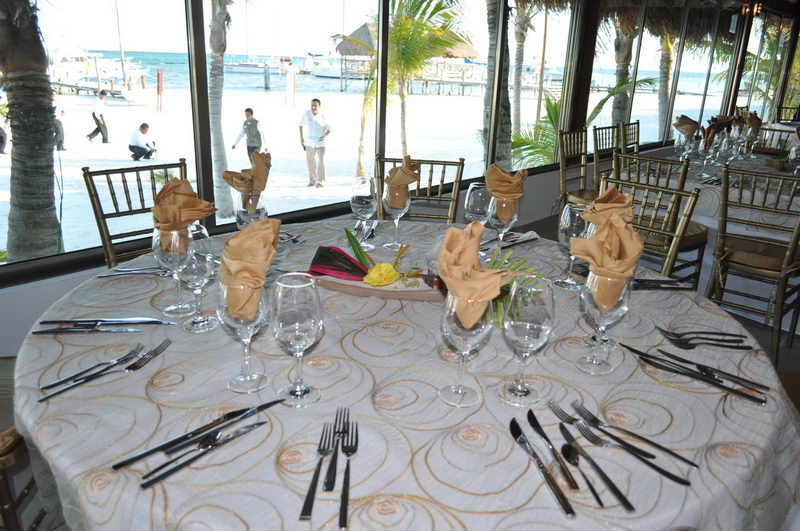 Elegant table setting with gold napkins and ocean view of the Maroma pier and boats from the beachfront restaurant, Riviera Maya