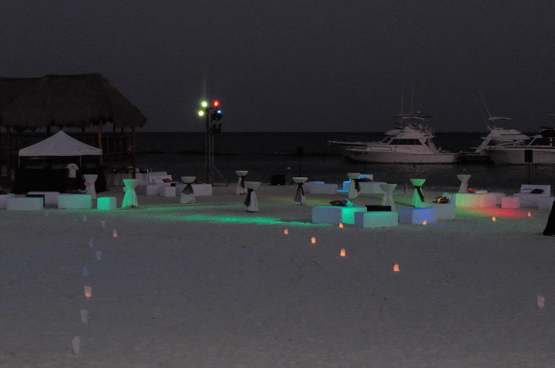 Nighttime beach party setup with colorful LED lighting, candle luminarias and sport fishing yachts docked at Marina Maroma near Cancun