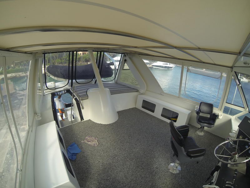 Flybridge cubierto del yate de 60 pies con timón y asientos de capitán, con vista a la marina de Puerto Aventuras