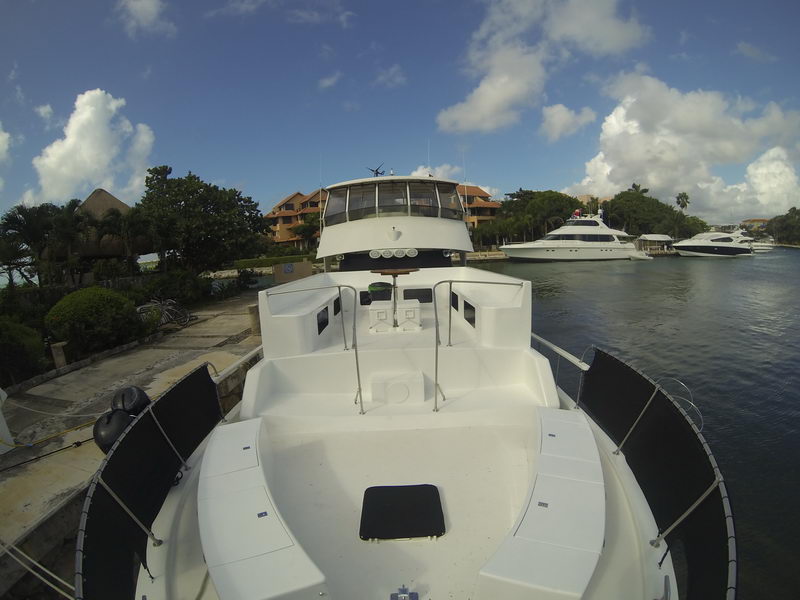 Proa amplia del yate de 60 pies con áreas para tomar el sol, atracado en la marina de Puerto Aventuras bajo cielo caribeño