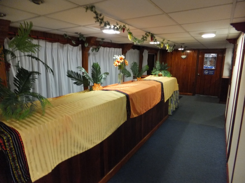 Buffet tables on the Princess boat dressed in yellow and orange linens with palm and floral décor for a tropical theme party