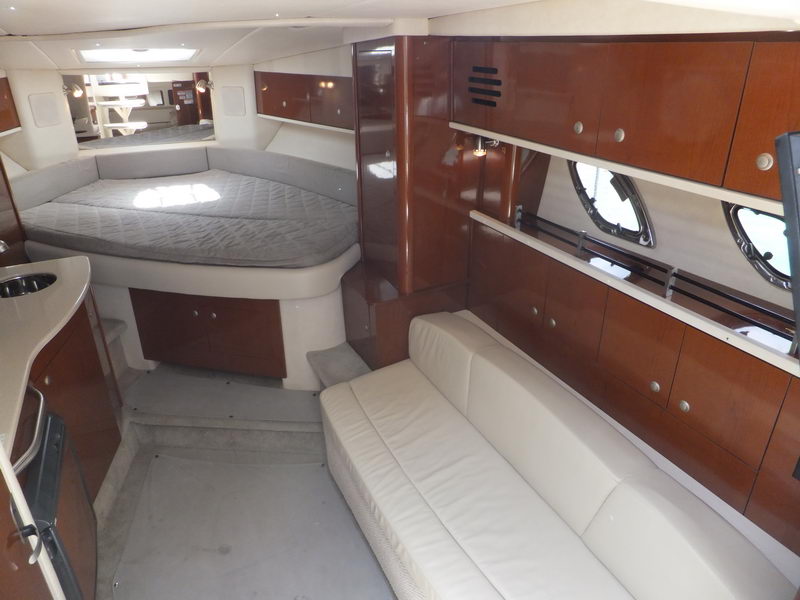 Elegant interior cabin of SeaRay Sundancer rental yacht in Cancun with V-berth double bed and cream leather salon sofa