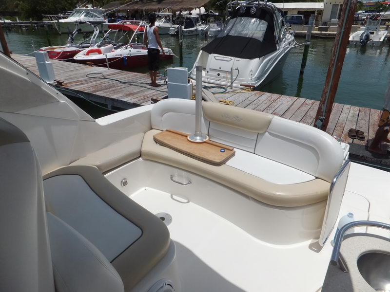 Cockpit aft lounge of SeaRay Sundancer sport yacht with teak table and plush seating at Cancun marina dock