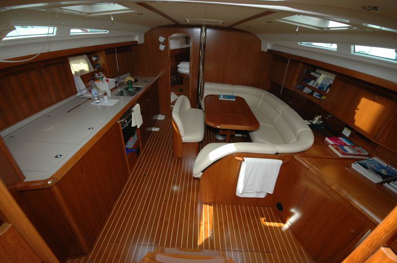 Elegant salon with white leather seating, teak floors and galley aboard Jeanneau Sun Odyssey 45 luxury sailboat Cancun