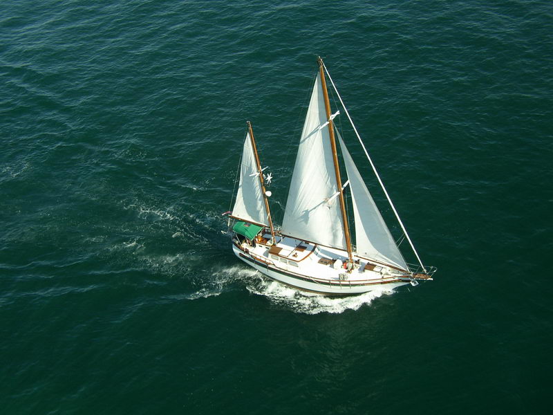 Aerial view of 55 ft wooden ketch Calypsa under full sail on open Caribbean Sea, Hollywood movie star sailboat charter Cancun