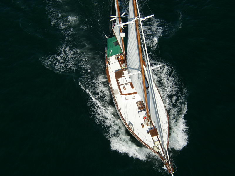 Overhead aerial view of 55 ft wooden ketch Calypsa at full speed showing teak deck layout, luxury Caribbean sailing charter