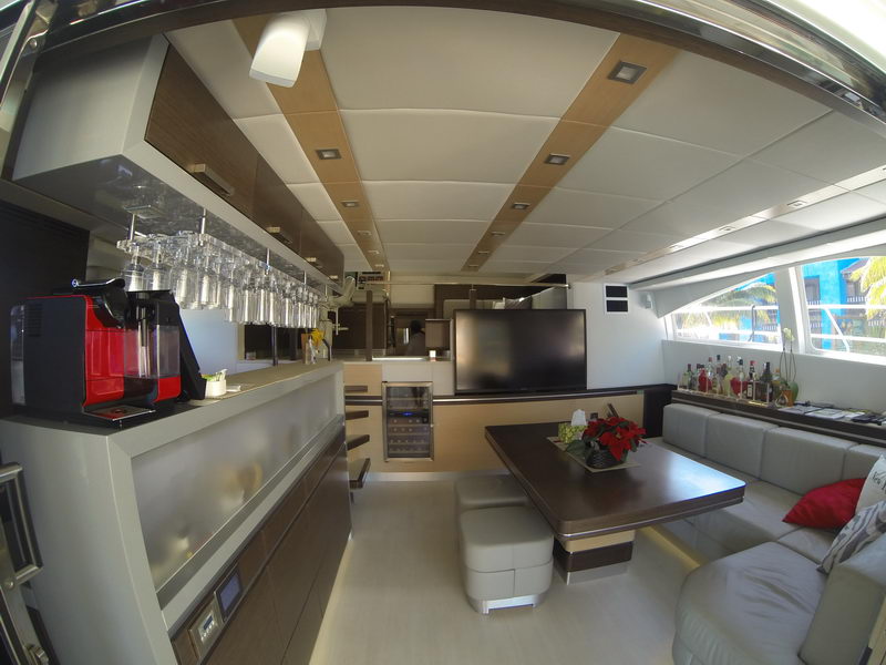 Main salon bar of the 66 ft Sunreef power catamaran with espresso machine, stemware rack, TV and lounge seating, luxury yacht charter Cancun