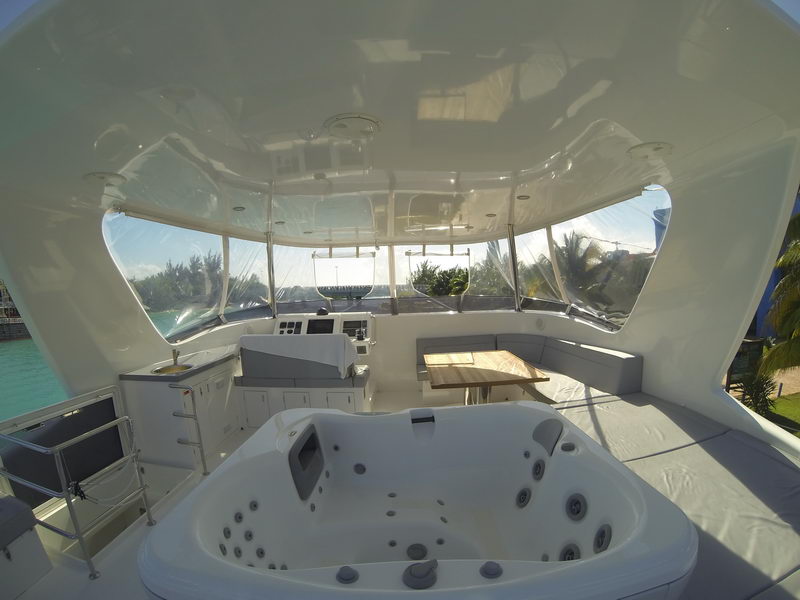 Enclosed flybridge of the 66 ft Sunreef catamaran with jacuzzi, helm station and lounge overlooking the Cancun lagoon
