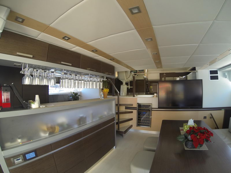 Galley and bar area of the 66 ft Sunreef catamaran with wine cooler, glassware and flat-screen TV, Cancun luxury yacht rental